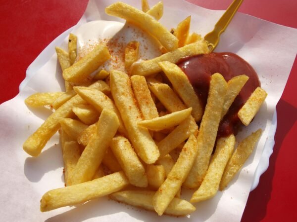 Delicious crispy French fries served with ketchup and mayonnaise on a paper plate