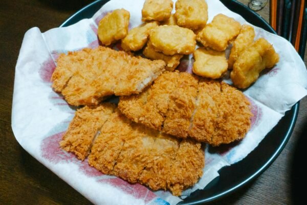 A plate of crispy fried chicken strips and nuggets served on a paper-lined dish.